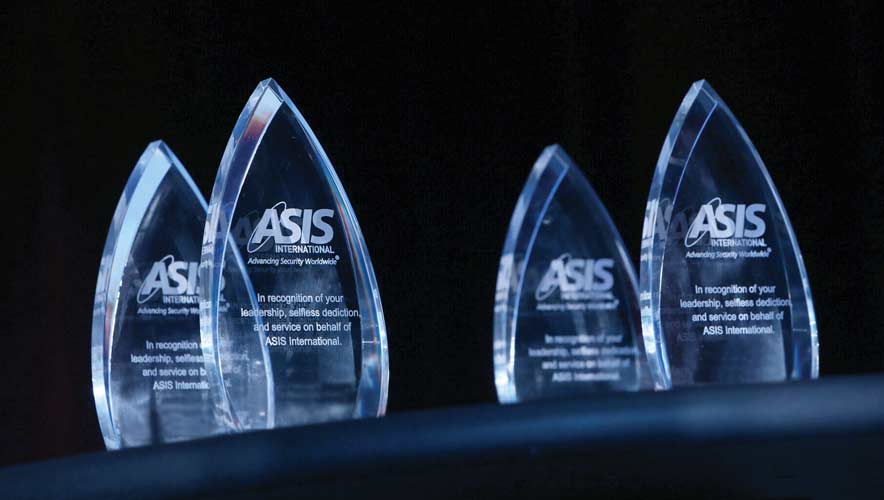 Glass awards with the ASIS logo etched on them sit on a black table.  ASIS is recognizes outstanding individuals and chapters for their accomplishments during 2021-22. 
