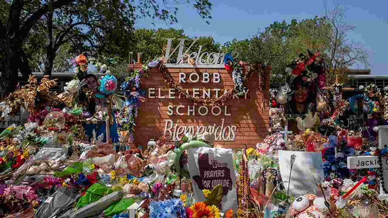 A memorial of flowers adorn a welcome sign at Robb Elementary School in Uvalde, Texas.  